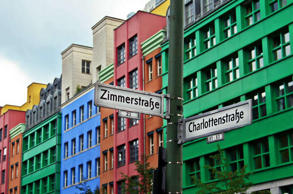 Street sign pointing to Zimmerstrasse and Charlottenstrasse with Quartier Schützenstrasse at background 