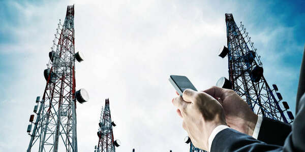 Homme d'affaires utilisant un téléphone portable avec Telecommunication tours avec antennes TV et antenne parabolique sur ciel bleu