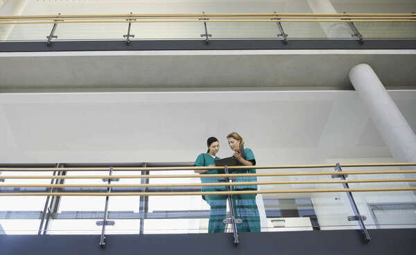Low angle view of two female medical workers looking at chart on balcony