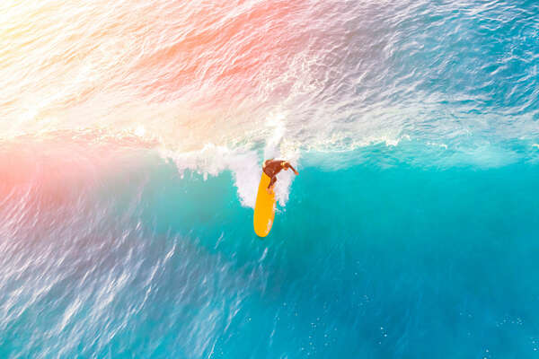 Surfer on a yellow surfboard in the ocean on a sunny day